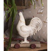 Vidéki vintage stílusú, 15 cm hosszú és 17 cm magas, kiskocsin álló nosztalgikus kakas figura..